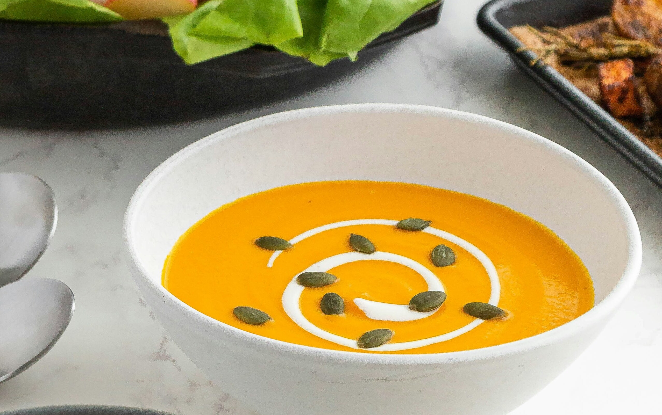 Kürbiscremesuppe mit Sahnehaube und Kürbiskernen.